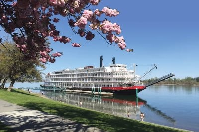 Riverboat docked at the Richland waterfront beneath flowering trees
